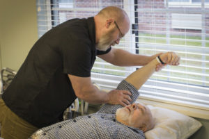 a physical therapist helps a man with his shoulder